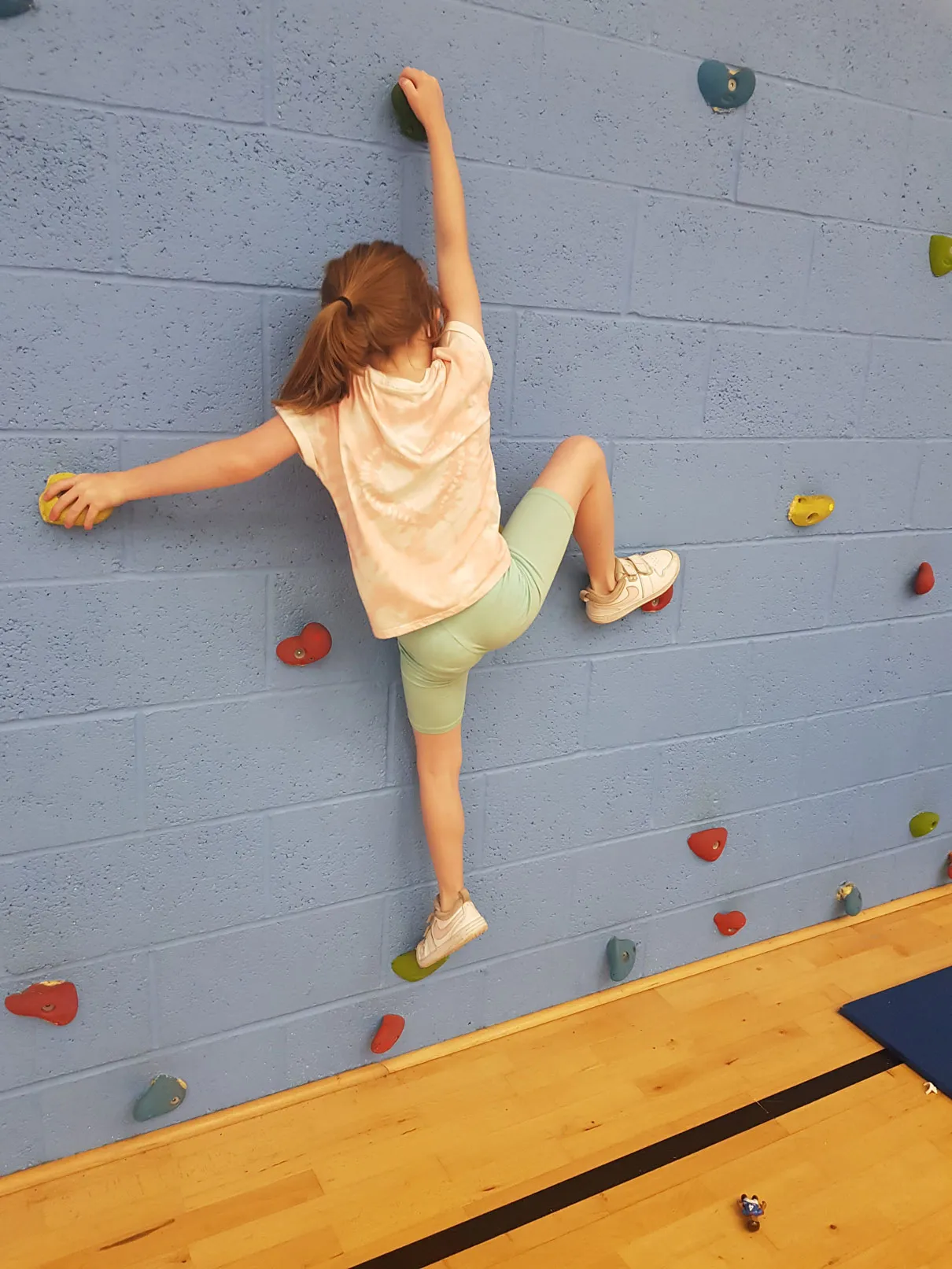 girl climbing on blue wall